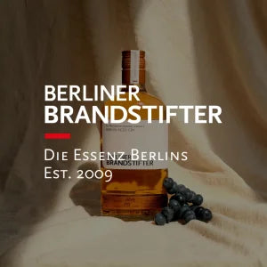 Produktfoto einer klaren Spirituosen‑Flasche mit elegantem Etikett auf hellem Untergrund
